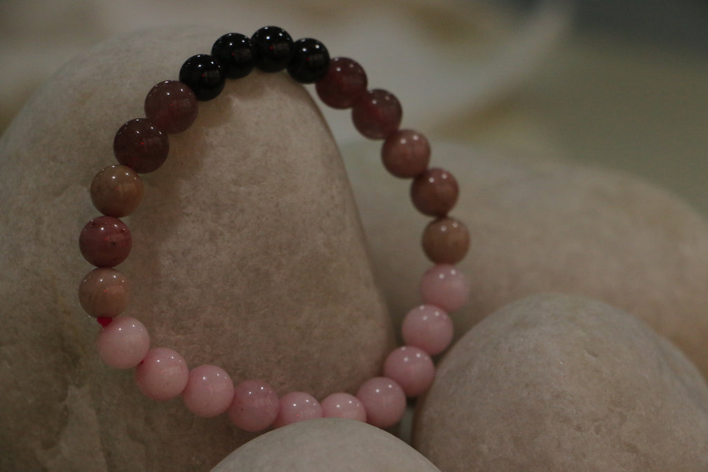 Pink beaded bracelet on a stone surface