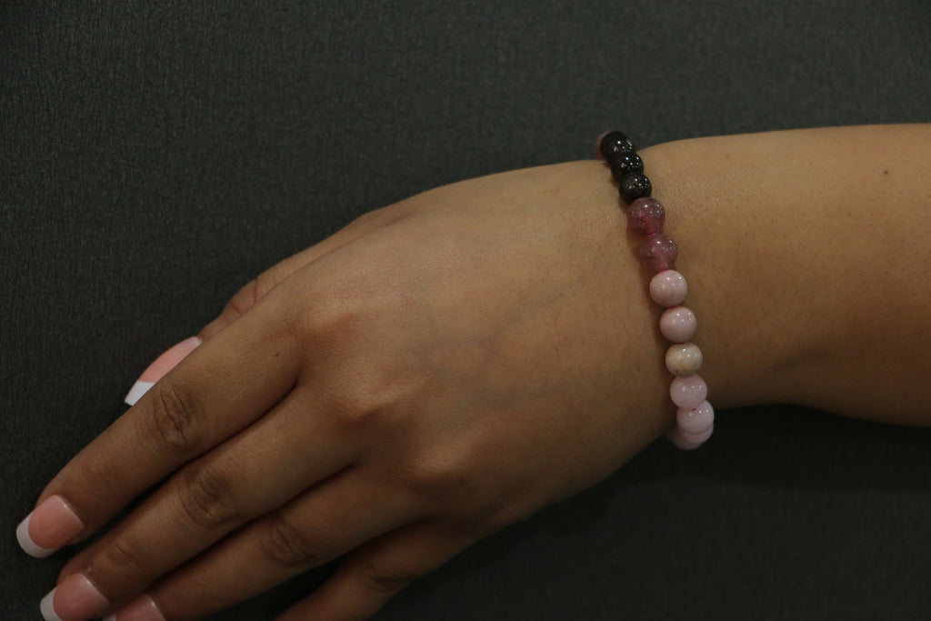 Hand wearing a beaded bracelet on a dark background