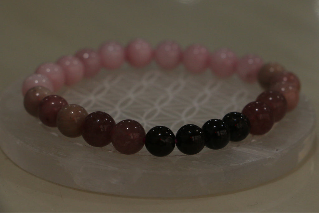 Beaded bracelet with pink, red, and black beads on a white surface